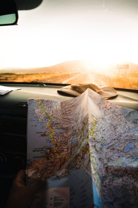 A bright sun in the background with a car dashboard view and a map sitting on the dashboard. on the topic of home address on your resume